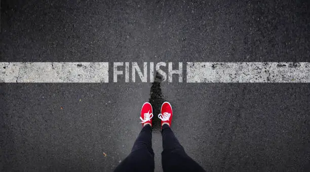 Red shoes standing next to finish line painted text