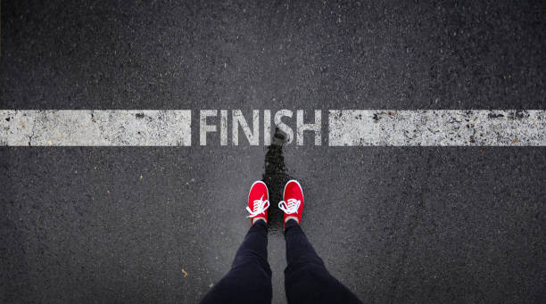 red shoes standing next to finish line painted text - finish line imagens e fotografias de stock