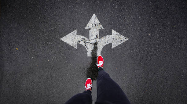 istock Red shoes standing next to arrows painted in road 686051146