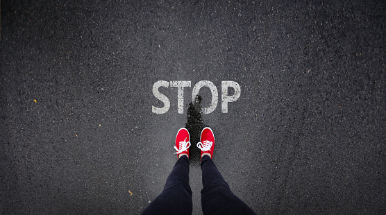 Red shoes standing next to stop sign painted on ground