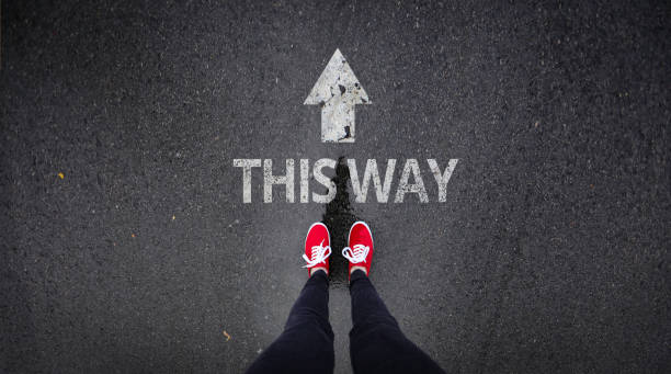 istock Red shoes standing next to this way painted on road 686051162