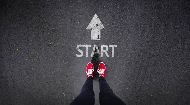 Red shoes standing next start with arrow painted on ground