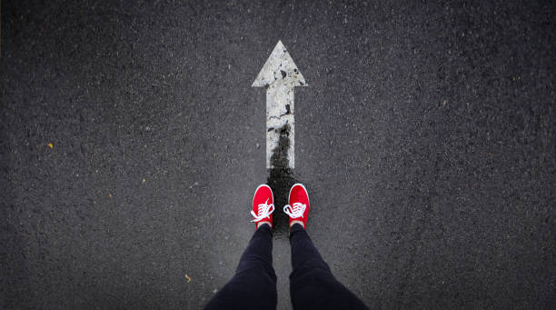 istock Red shoes standing next to arrow painted 686051184