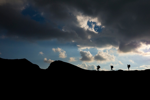 Silhouette of mountaineers walking over the mountain