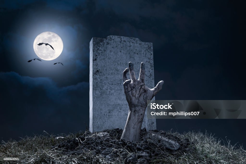 Zombie Hand Halloween Graveyard Night Monster Scary A zombie hand bursting through the grave in a graveyard on Halloween night under a full moon with vampire bats. Zombie Stock Photo