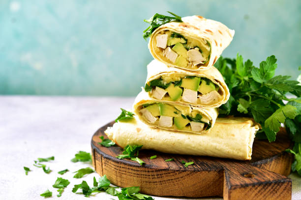 Chicken avocado burritos on a wooden cutting board o