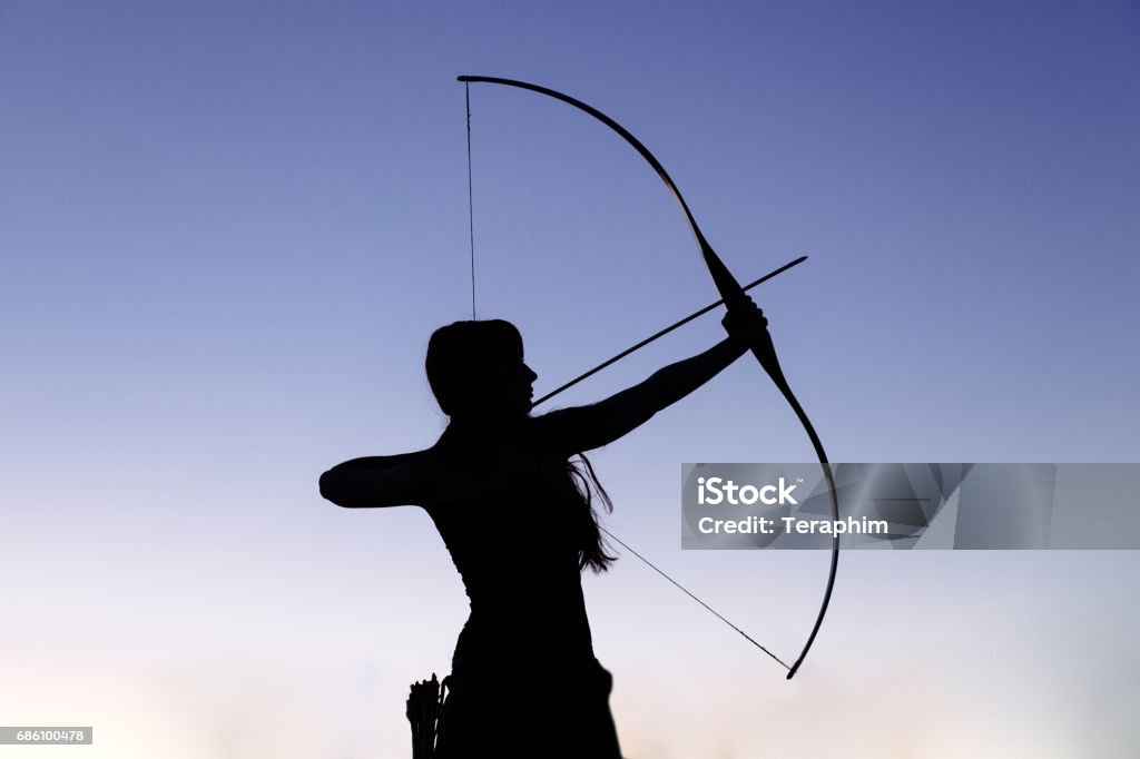 Female ginger hair archer shooting targets with her bow and arrow. Concentration, target, success concept Female ginger hair archer shooting targets with her bow and arrow. Concentration, target, success concept. Copy space text. Archery Stock Photo