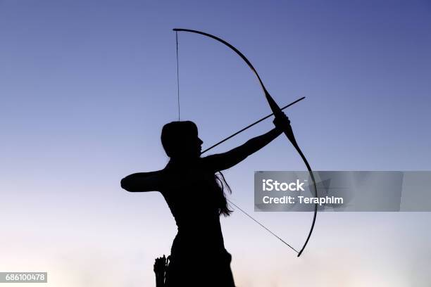 Female Ginger Hair Archer Shooting Targets With Her Bow And Arrow Concentration Target Success Concept Stock Photo - Download Image Now