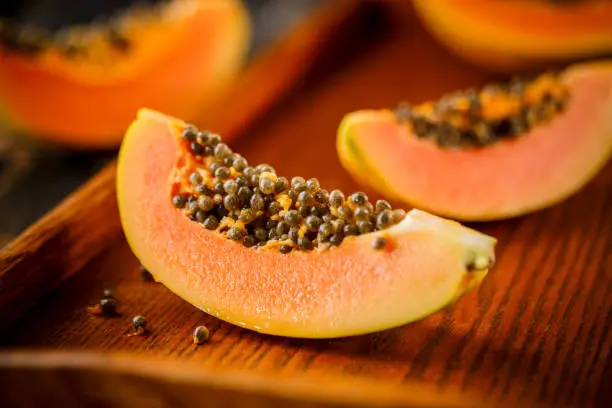 Photo of Halved and whole papaya fruits on the background