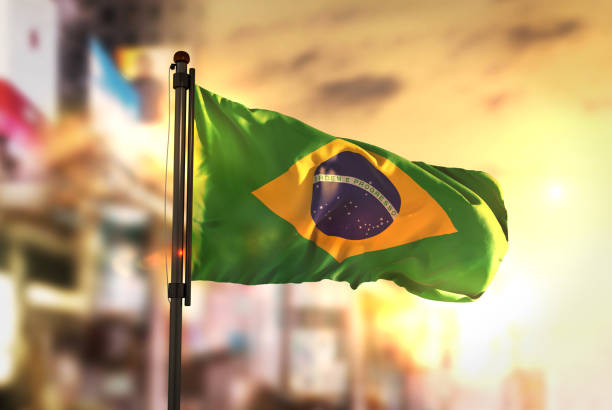 brazil flag against city blurred background at sunrise backlight - brasil imagens e fotografias de stock