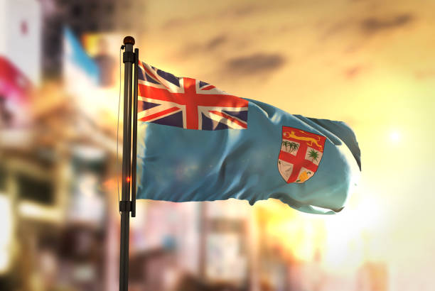 Fiji Flag Against City Blurred Background At Sunrise Backlight Fiji Flag Against City Blurred Background At Sunrise Backlight suva photos stock pictures, royalty-free photos & images