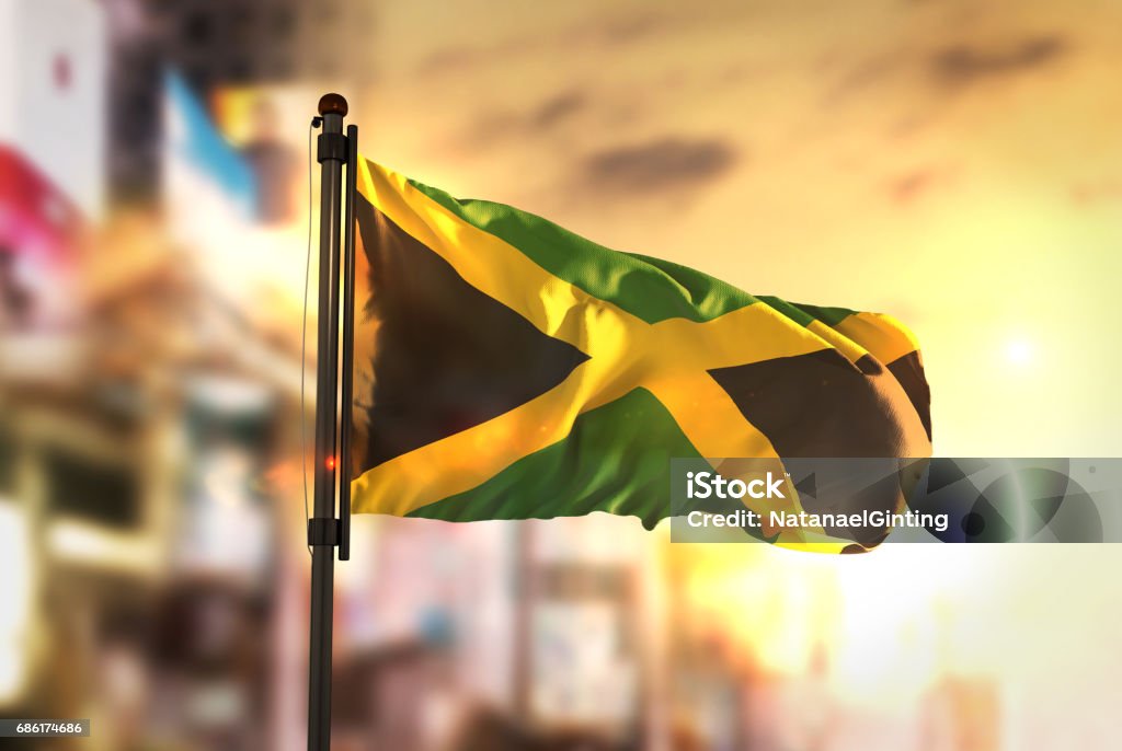 Jamaica Flag Against City Blurred Background At Sunrise Backlight Jamaican Flag Stock Photo