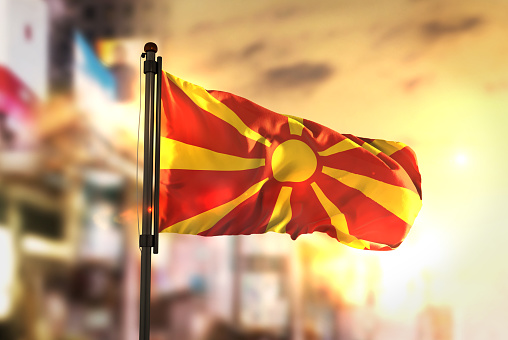 Republic of Macedonia Flag Against City Blurred Background At Sunrise Backlight