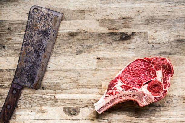 istock Raw beef rib with a vintage chopping knife on a old oak wood table 686178672