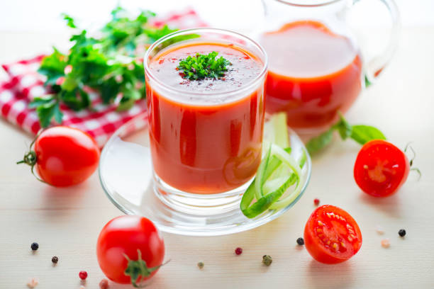 istock tomato juice in glass, jug with greenery, basil, cutted tomato fruit and dry pepper on light table, concept healthy eating, close up 686178700