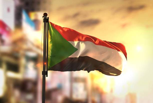 Sudan Flag Against City Blurred Background At Sunrise Backlight Sudan Flag Against City Blurred Background At Sunrise Backlight khartoum stock pictures, royalty-free photos & images