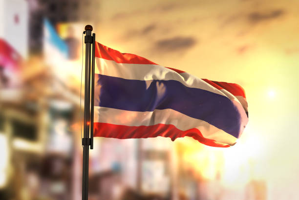 Thailand Flag Against City Blurred Background At Sunrise Backlight Thailand Flag Against City Blurred Background At Sunrise Backlight thai flag stock pictures, royalty-free photos & images