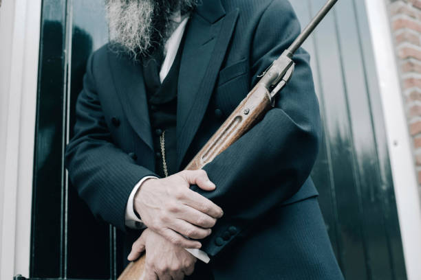 istock Hands of man holding rifle while leaning against window shutters. 686205190