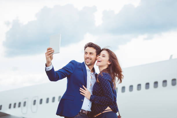istock Smiling young couple talking selfie in front of airplane 686218668