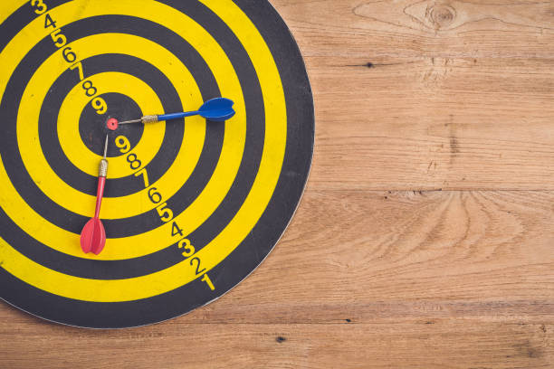istock Dart arrow and dartboard on brown wooden background. Composition white free space for text or design 686228700