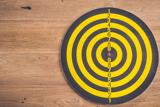 istock Dart arrow and dartboard on brown wooden background. Composition white free space for text or design 686228772