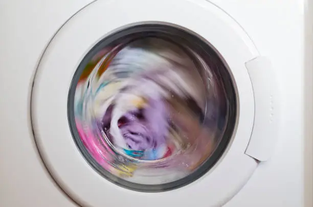 Photo of Washing machine door with rotating garments inside