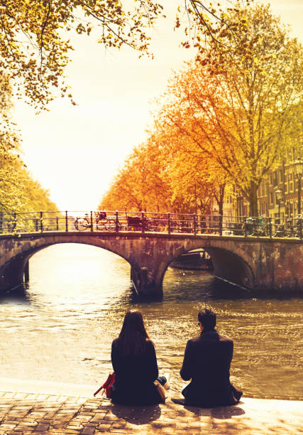 몇 친구 또는 연인 운하와 강에 보이는 제방 및 암스테르담의 다리에 휴식. - netherlands couple people amsterdam 뉴스 사진 이미지