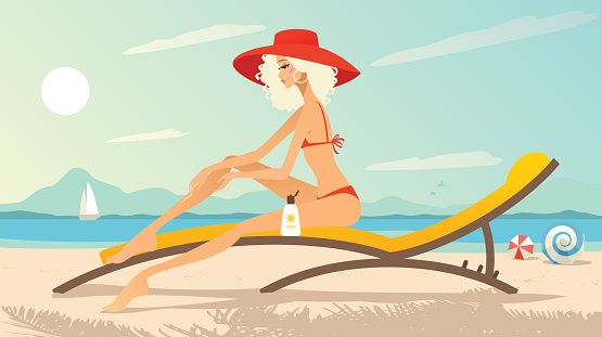 Young woman sitting in a lounge chair on the beach applying suntan lotion.
