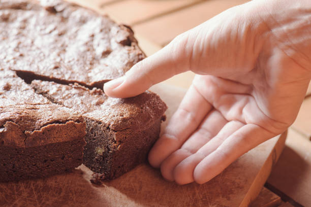 istock Hand taking piece of chocolate brownie cake with walnuts 686257716