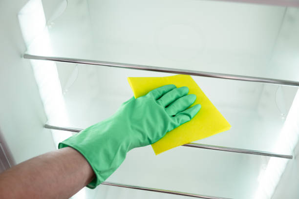 istock Man's hand in green gloves cleaning the open kitchen fridge 686261086