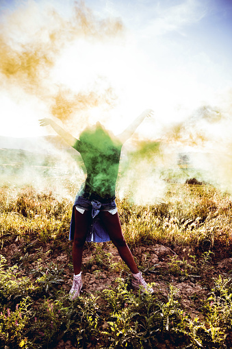 Friends holding smoke bombs having fun in a field during a road trip