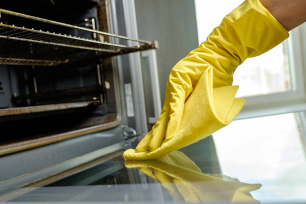 istock Man with rag and rubber gloves cleaning kitchen stove 686261142