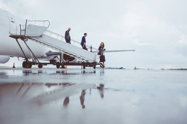 gruppo di passeggeri che sbarca sull'aereo - runway airport sky wet foto e immagini stock