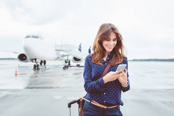 Business woman using a smart phone in front of airplane
