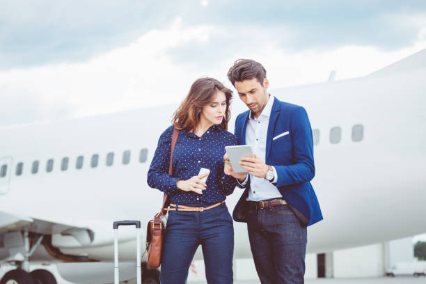 istock Business colleagues using digital tablet in front of airplane 686267110
