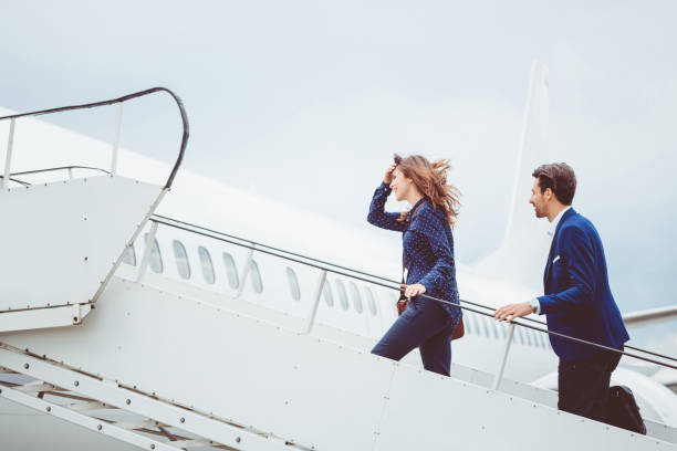 Two business people boarding airplane Two business people boarding airplane, going on business trip. flight of steps stock pictures, royalty-free photos & images