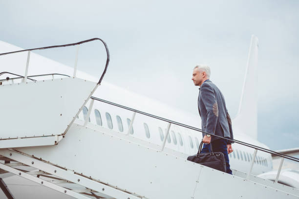 istock Mature man walking up stairs into airplane 686271374