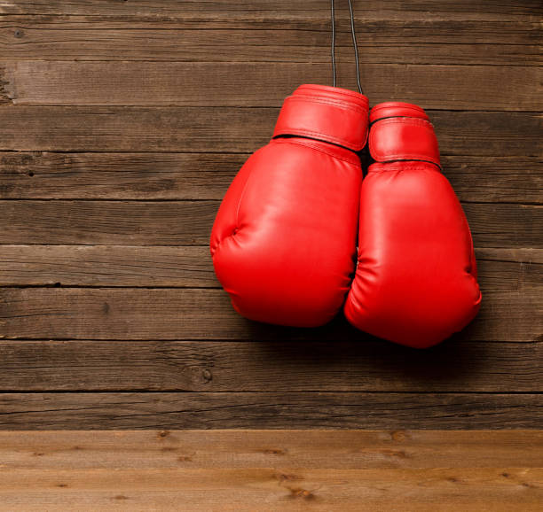 istock Two red boxing gloves hung on a wooden brown background, empty space 686278434