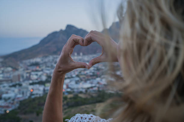istock Young woman making heart shape frame in Cape Town at sunrise 686291698
