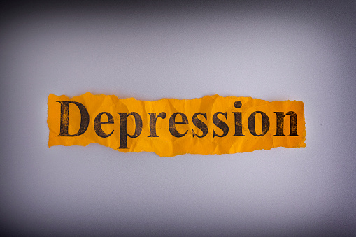 Torn crumpled piece of yellow paper with the word Depression. Concept image.