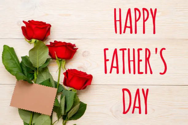 happy father's day, 3 red roses with empty craft paper card on rustic table