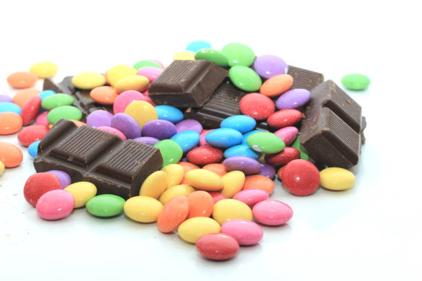 Chocolate filled candies in various bright colors and pieces of a chocolate bar