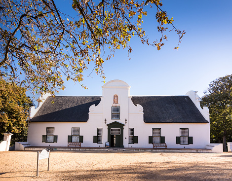 The manor house at Groot Constantia proudly sits on the wine farm, welcoming tourists from all over the world. Located near cape town on the back side of Table Mountain. It's a historic point of interest, being built in 1685. Shot in April 2017 during Fall.