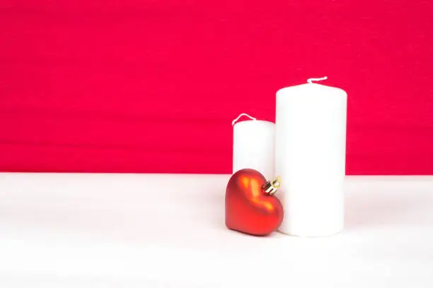 red heart and white candles with red background