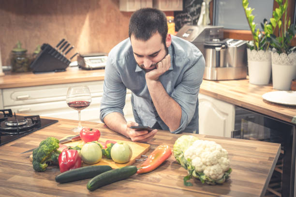 istock Man reading recipe on cell phone and cooking. 686318686