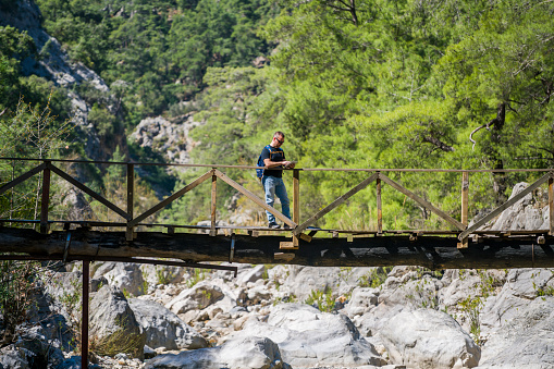 A wooden Bridge on foliage crossing a small stream.