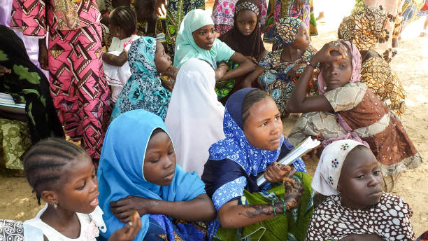 octubre de 2013, maradi, níger: chicas de escuela musulmana conseguir protección contra el calor extremo en níger bajo una sombra de un árbol, fuera de su escuela. - niger fotografías e imágenes de stock