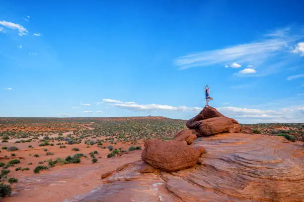 Person doing a standing yoga pose on the top of a sandstone formation rock in Horseshoe Bend Arizona