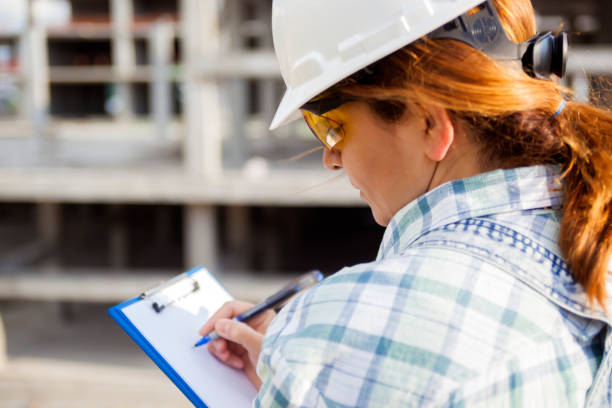 Female architect writing on clipboard at construction site Female architect writing on clipboard at construction site inspector stock pictures, royalty-free photos & images