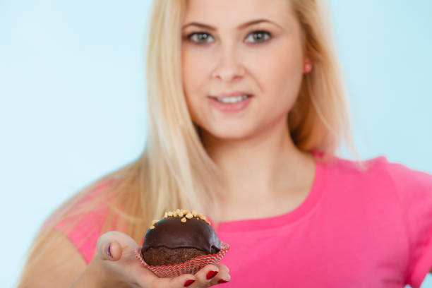 istock Woman holding chocolate cupcake about to bite 686371156